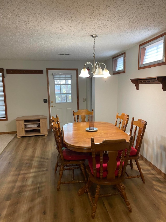 dining room with a chandelier, wood-type flooring, and a textured ceiling