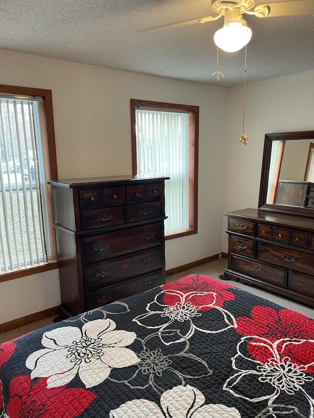 bedroom with a textured ceiling, light colored carpet, and ceiling fan