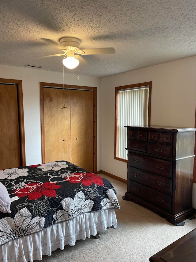 bedroom with a textured ceiling, ceiling fan, and light carpet