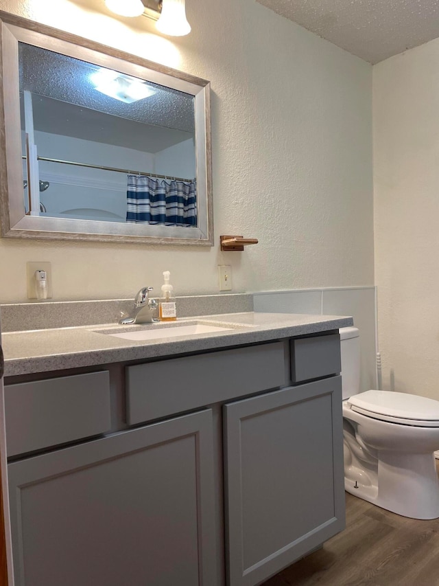 bathroom with hardwood / wood-style flooring, vanity, toilet, and a textured ceiling