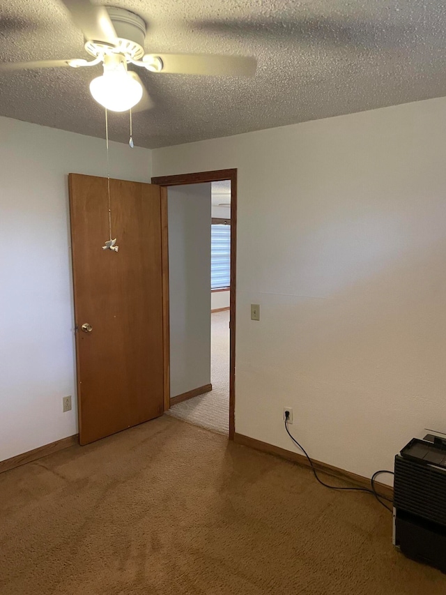 carpeted spare room featuring ceiling fan and a textured ceiling