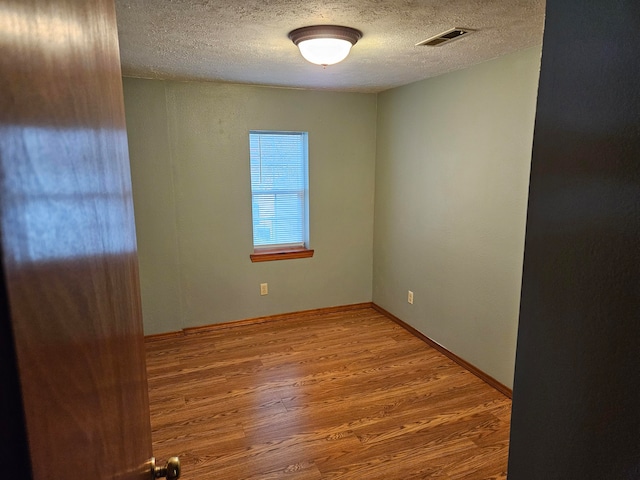 spare room featuring a textured ceiling and wood-type flooring