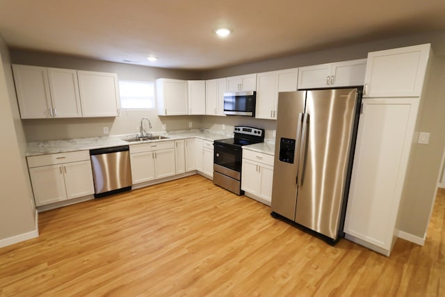 kitchen featuring appliances with stainless steel finishes, light hardwood / wood-style flooring, white cabinetry, and sink