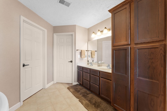 bathroom with vanity, a textured ceiling, and tile patterned flooring