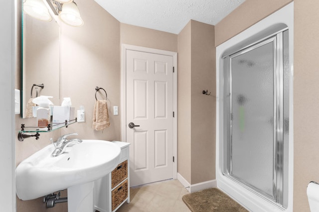 bathroom featuring a shower with door, a textured ceiling, and tile patterned floors