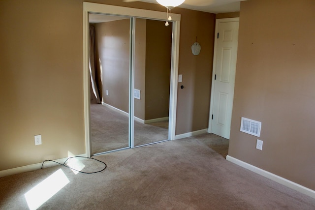 unfurnished bedroom with light carpet and a closet