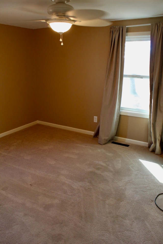 carpeted spare room featuring ceiling fan