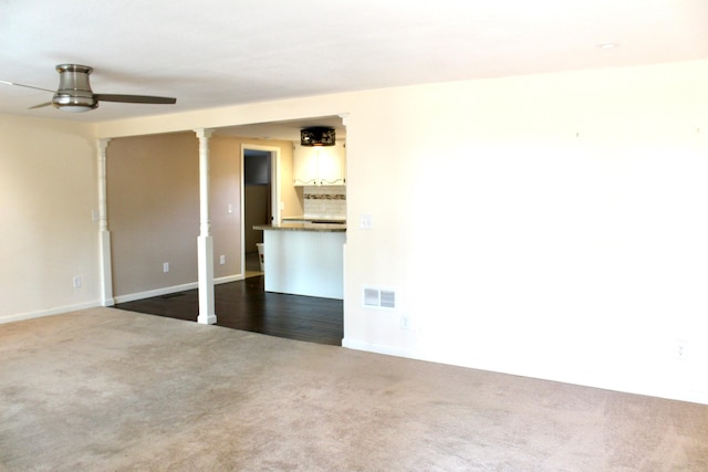 carpeted spare room featuring ornate columns and ceiling fan