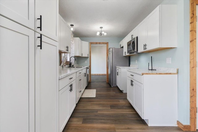 kitchen featuring sink, a textured ceiling, white cabinetry, a notable chandelier, and dark hardwood / wood-style floors