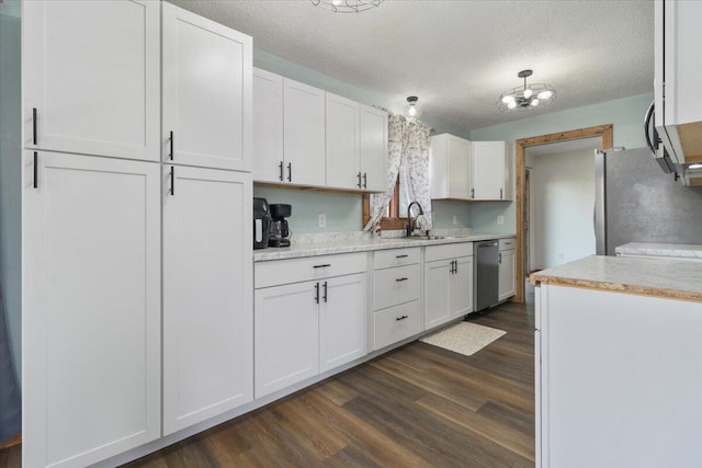 kitchen with dark hardwood / wood-style floors, stainless steel appliances, sink, white cabinetry, and a textured ceiling