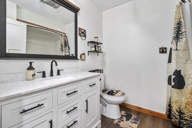 bathroom featuring toilet, a shower with curtain, hardwood / wood-style floors, vanity, and a textured ceiling