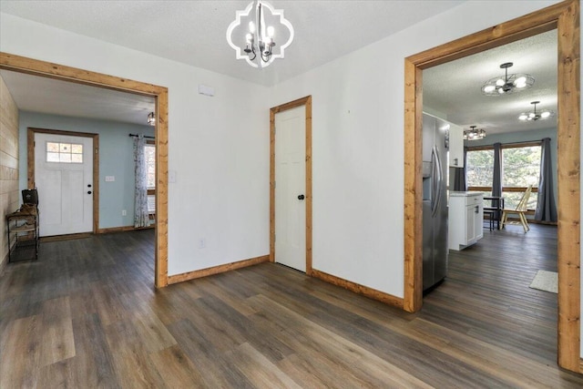 interior space with a textured ceiling, a notable chandelier, and dark hardwood / wood-style floors