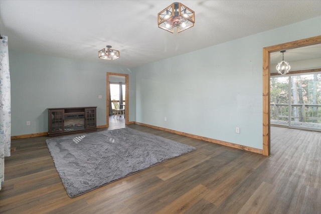 unfurnished living room with dark hardwood / wood-style floors, a chandelier, and a fireplace