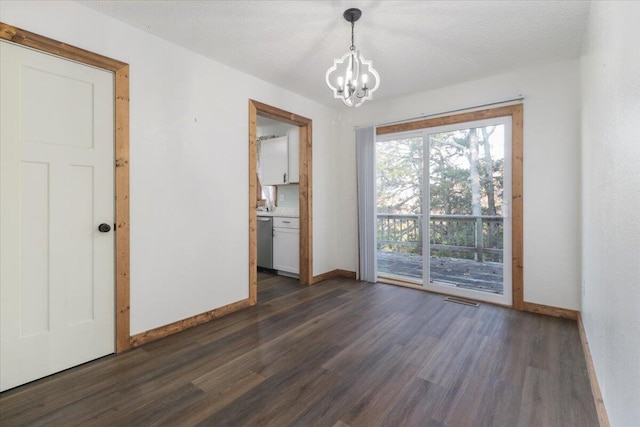 spare room with a chandelier, a textured ceiling, and dark hardwood / wood-style flooring