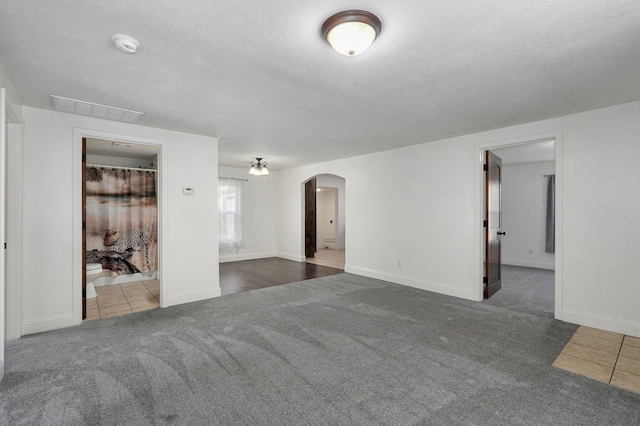 spare room featuring a textured ceiling and dark colored carpet