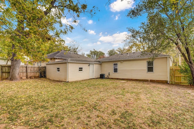 rear view of house with cooling unit and a lawn