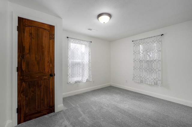 spare room featuring a textured ceiling and carpet