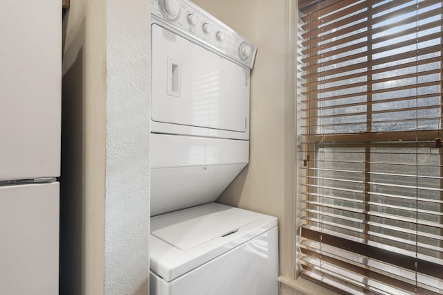 washroom featuring stacked washer / dryer and a healthy amount of sunlight