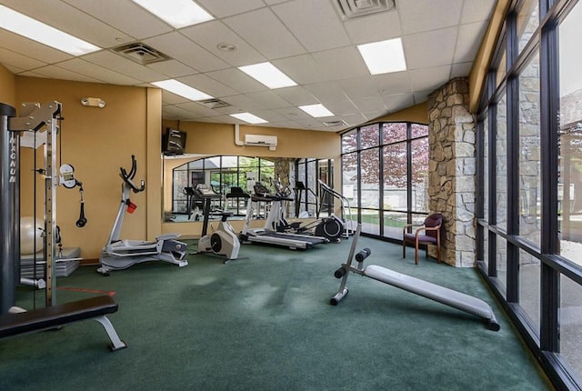 workout area with a drop ceiling, a wall mounted AC, and carpet flooring