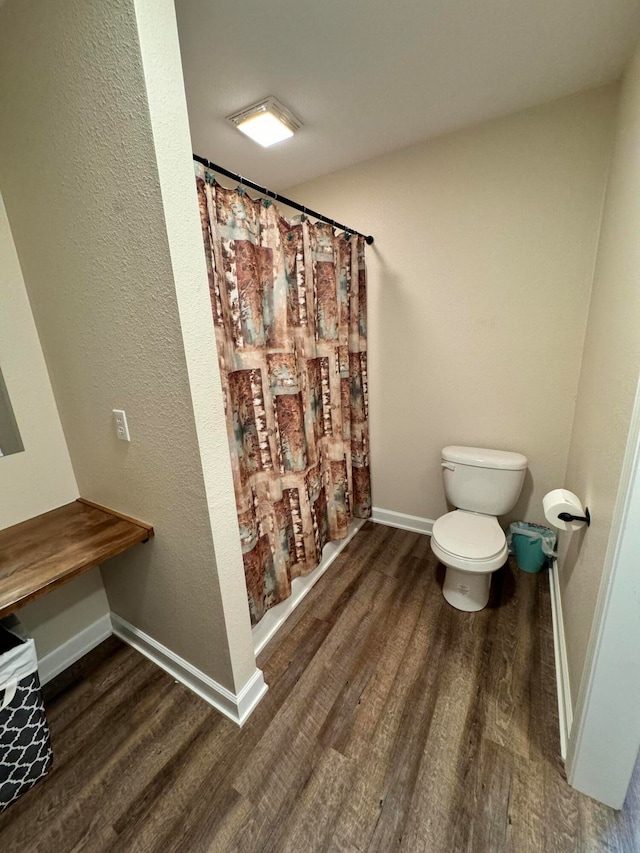 bathroom with a shower with shower curtain, wood-type flooring, and toilet