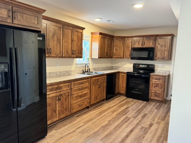 kitchen featuring black appliances, sink, and light wood-type flooring