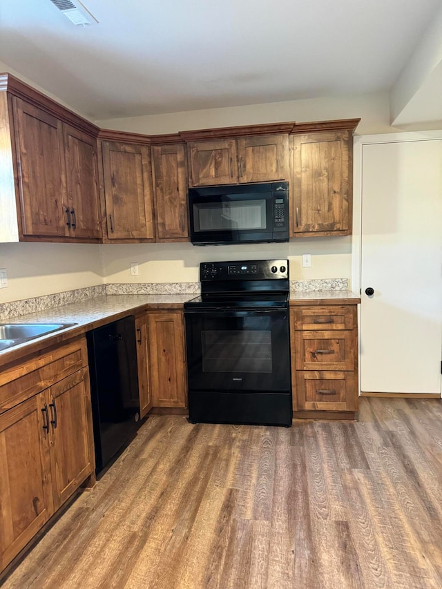 kitchen with sink, black appliances, and dark hardwood / wood-style flooring