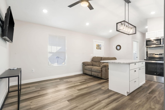 kitchen featuring hanging light fixtures, appliances with stainless steel finishes, white cabinetry, vaulted ceiling, and dark hardwood / wood-style floors