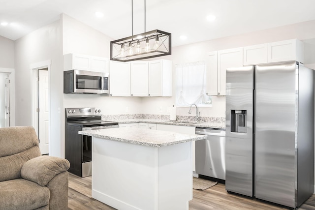 kitchen featuring stainless steel appliances, a center island, decorative light fixtures, and white cabinets