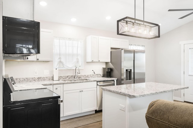 kitchen with sink, a kitchen island, white cabinetry, stainless steel appliances, and decorative light fixtures