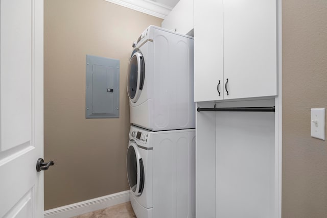 laundry room featuring cabinets, crown molding, electric panel, and stacked washer and dryer