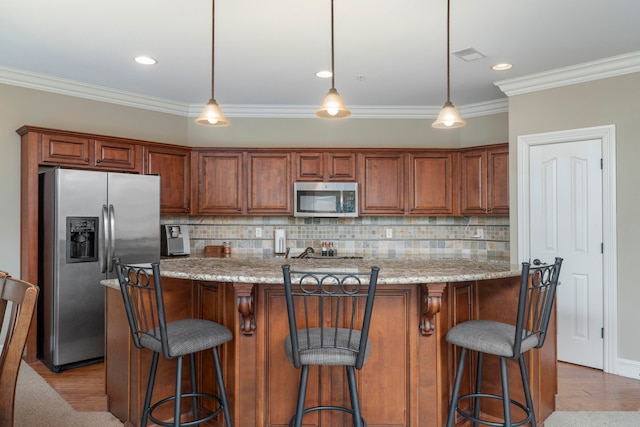 kitchen with backsplash, appliances with stainless steel finishes, pendant lighting, and light wood-type flooring