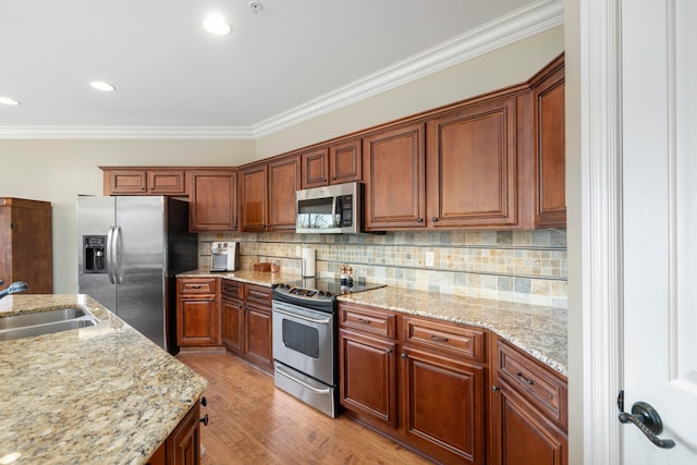 kitchen featuring light stone counters, stainless steel appliances, sink, and light wood-type flooring