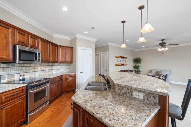 kitchen featuring an island with sink, a breakfast bar, light hardwood / wood-style flooring, stainless steel appliances, and sink