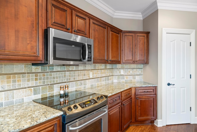 kitchen with tasteful backsplash, stainless steel appliances, light stone counters, hardwood / wood-style flooring, and ornamental molding