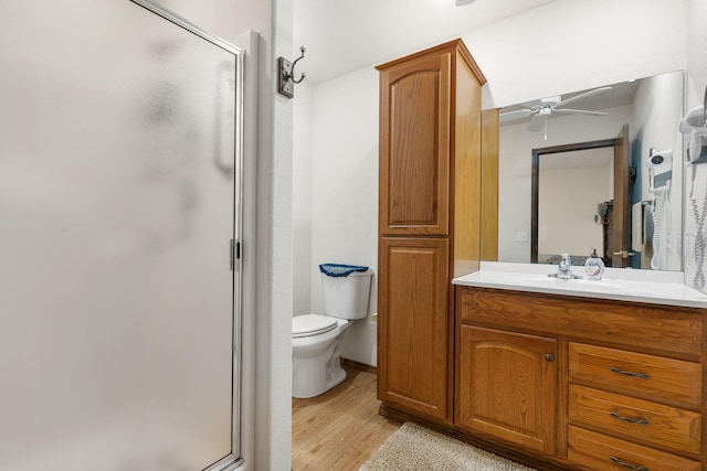 bathroom with ceiling fan, walk in shower, hardwood / wood-style flooring, toilet, and vanity