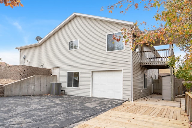 back of property with a garage, a deck, and central air condition unit