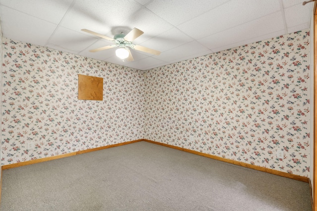 carpeted spare room featuring a drop ceiling and ceiling fan