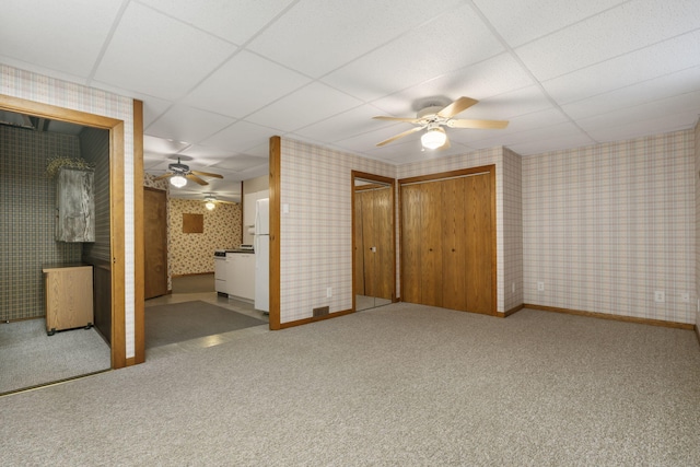 unfurnished bedroom with white fridge, ensuite bath, and a drop ceiling