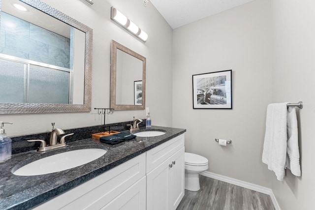 bathroom featuring a textured ceiling, walk in shower, wood-type flooring, toilet, and vanity