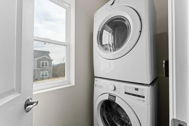 laundry area with stacked washer / dryer and a healthy amount of sunlight