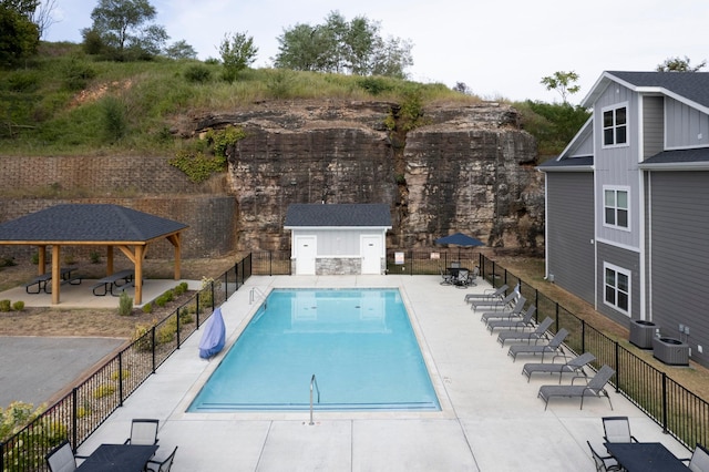 view of swimming pool featuring a gazebo, a patio area, an outdoor structure, and central AC unit