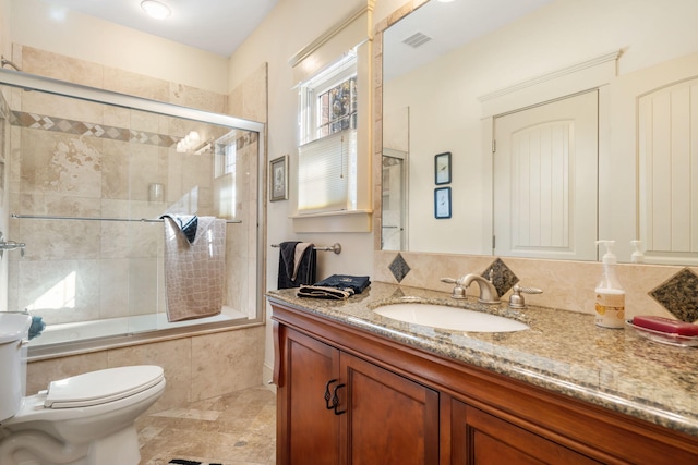 full bathroom featuring vanity, bath / shower combo with glass door, and toilet