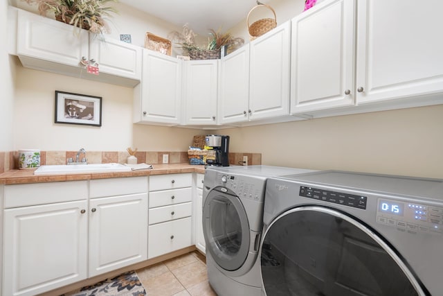 laundry room with light tile patterned floors, cabinets, sink, and separate washer and dryer