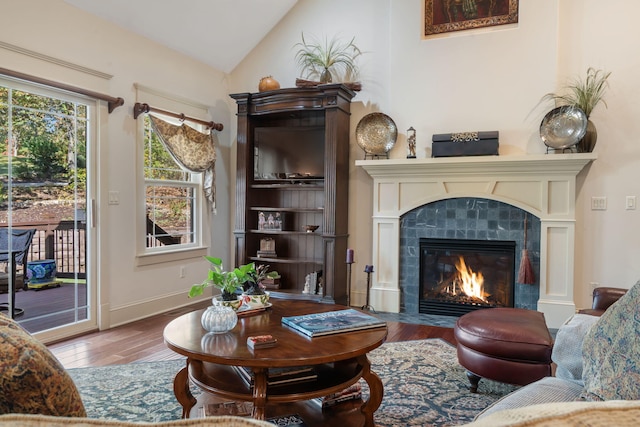 sitting room featuring lofted ceiling, a tiled fireplace, and wood-type flooring