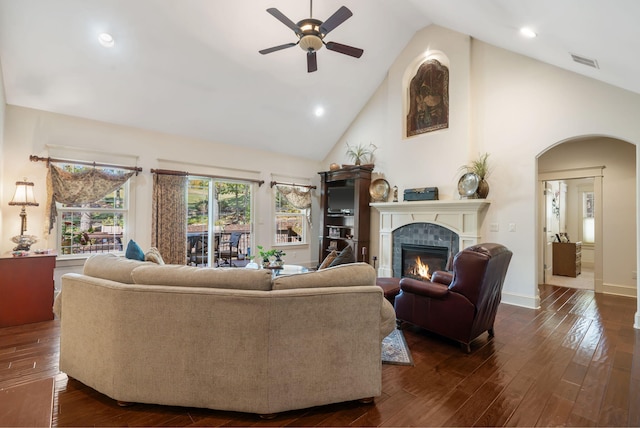 living room featuring dark wood-type flooring, a tiled fireplace, high vaulted ceiling, and ceiling fan