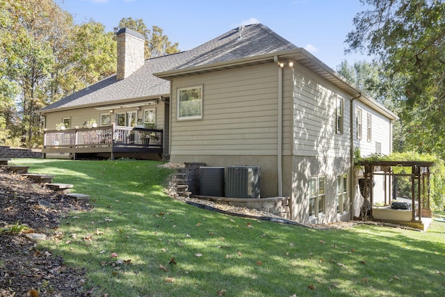 rear view of property featuring central air condition unit, a deck, and a lawn