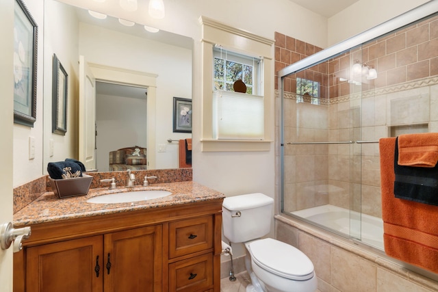 full bathroom with vanity, enclosed tub / shower combo, and toilet