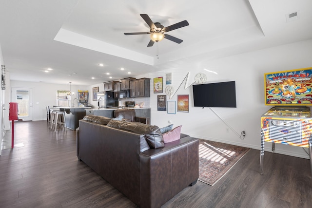 living room featuring ceiling fan, a raised ceiling, and dark hardwood / wood-style flooring