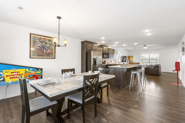 dining space featuring dark hardwood / wood-style floors and ceiling fan with notable chandelier