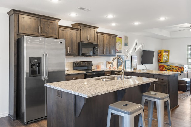 kitchen with sink, black appliances, a kitchen bar, and dark hardwood / wood-style flooring